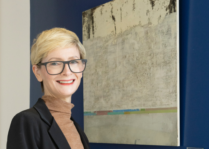 Woman standing beside painting from art collection