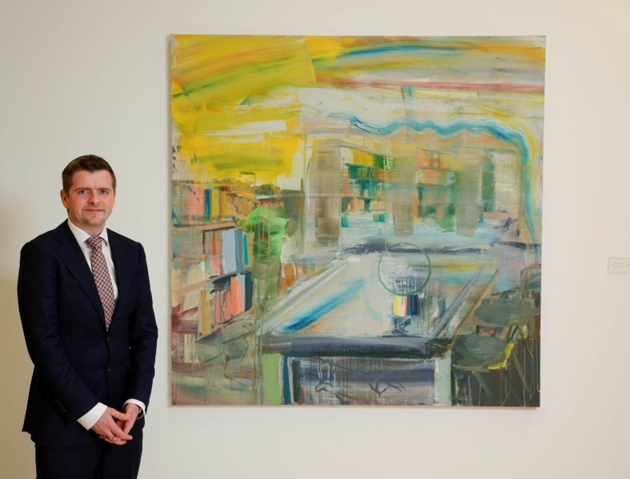 Man standing beside painting in corporate setting